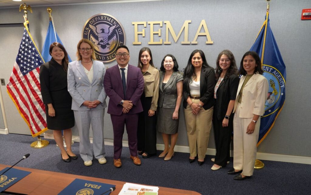 A group of men and women standing in front of the FEMA sign.